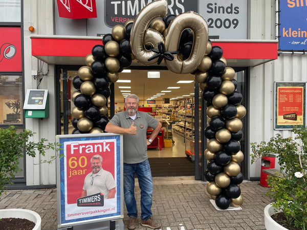 Frank van Kleinkantoor wordt 60 jaar voor de winkel met gouden ballonnenboog